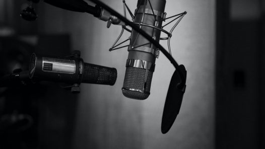 Third Culture Africa 7 Ways to use a Podcast for an entrepreneur podcast microphones with one having pop shield and facing up side down in a room with black background