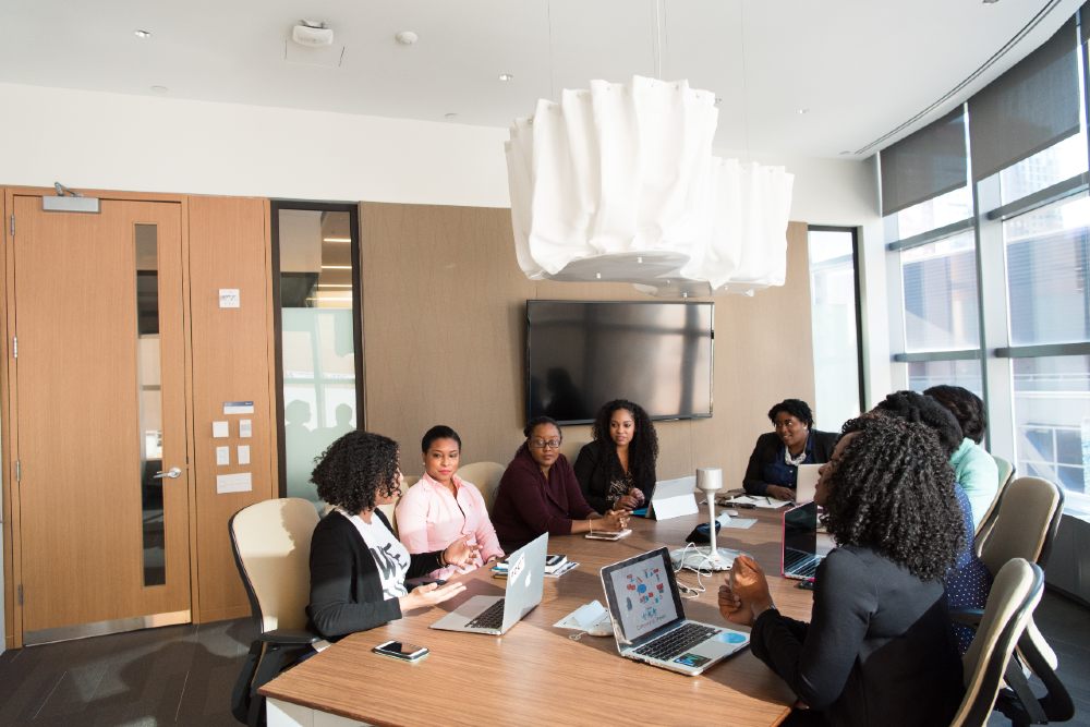 Third-Culture-Africa 5 things famous entrepreneurs have in common women having meeting in a boardroom with their laptop place on a brown table and a tv place the brown ward close a brown closet.