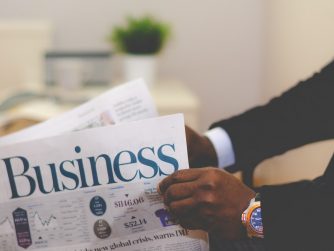 Third Culture Africa 7 leadership principles from famous entrepreneurs a man wearing black suit and white shirt with a blue wrist watch is holding a newspapper on which the word business is written