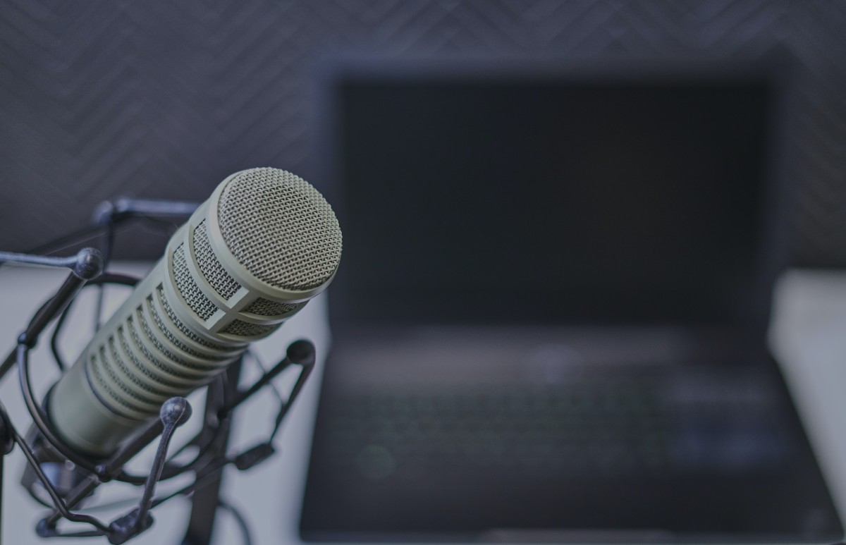Third Culture Africa How to start a business podcast a beige microphone with black support is place on a table close to an opened laptop