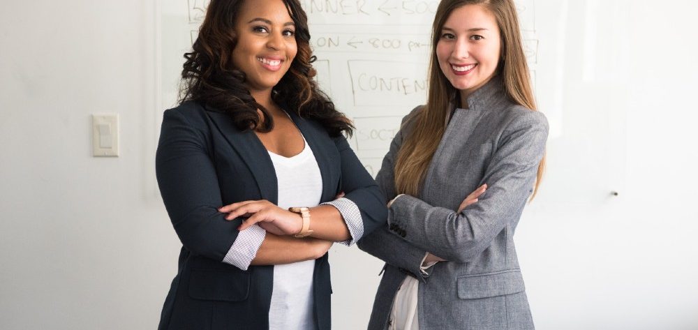Third Culture Africa Leadership vs Boss two ladies wearing black and beige jacketstanding in a room with white background and some writing in the white board